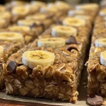 Close-up side view of banana oatmeal bars, showcasing a golden brown surface with chocolate chips.