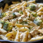 A close-up view of creamy pasta with shredded rotisserie chicken and broccoli.