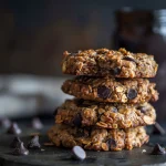 Close-up of a soft, chewy Greek yogurt cookie with dark chocolate chips against a blurred background.