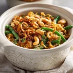 Close-up of a creamy green bean casserole in a crockpot with golden fried onions on top.
