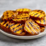 Close-up of glazed hot honey sweet potatoes with fresh parsley garnish.