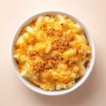 Close-up of creamy macaroni and cheese in a bowl with melted cheese on top.