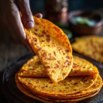 A close-up of golden-brown sweet potato tortillas on a wooden surface, beautifully textured.