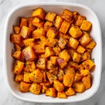 A close-up of caramelized roasted sweet potatoes with a warm, golden hue.