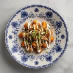 Close-up shot of soft, orange sweet potato gnocchi with a rustic blurred background.