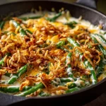 Close-up of a creamy green bean casserole topped with crispy fried onions.