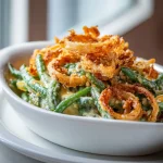 Close-up of a creamy green bean casserole topped with crispy fried onions.