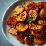 Close-up of garlic butter roasted sweet potatoes, golden and glistening.