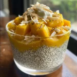 Close-up of a creamy mango coconut chia seed pudding in a glass.