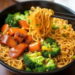 Close-up view of a vegan teriyaki noodle bowl filled with colorful vegetables.
