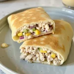 Close-up of a freshly made Tuna Melt Wrap showcasing melted cheese and colorful ingredients.
