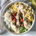 A close-up shot of a colorful Easy Street Corn Chicken Rice Bowl featuring diced chicken, corn, black beans, cherry tomatoes, and avocado.