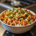 Close-up of a Buffalo Chicken Bowl featuring rice, shredded chicken, and vegetables in a warm light setting.