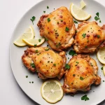 Close-up of golden-brown chicken thighs garnished with fresh parsley, surrounded by mixed vegetables.