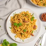 Close-up of caramelized onion pasta with a creamy sauce, garnished with fresh parsley.