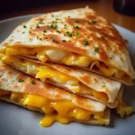 A close-up of a Cheddar Egg Quesadilla, golden brown tortillas, melted cheese, and bright green onions.