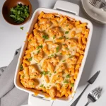 Close-up of a creamy Buffalo chicken pasta bake topped with green onions and melted cheese.