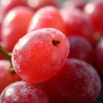 Close-up of frozen grapes coated in sour candy powder, with a soft blurred background.