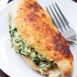 Close-up of baked Spinach Stuffed Chicken Breasts with creamy filling.