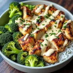 Close-up of a creamy garlic chicken bowl with broccoli and rice, garnished with grated parmesan.