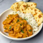 Close-up of a bowl of homemade butter chicken with creamy sauce and garnished with cilantro.