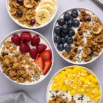 Close-up of a yogurt granola bowl topped with mixed berries and banana slices.