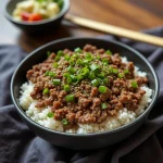 Close-up of a Korean Ground Beef Bowl with rice, green onions, and sesame seeds.