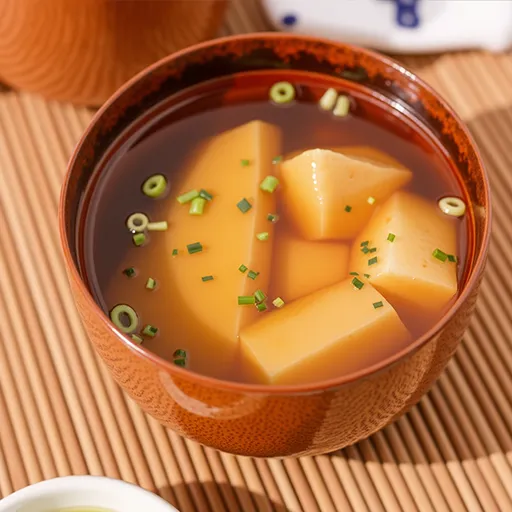 Delicious miso soup featuring seaweed and cubed silken tofu in soft lighting.
