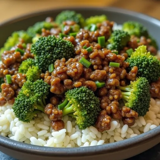A bowl of ground beef and broccoli drizzled with honey garlic sauce, served over rice.
