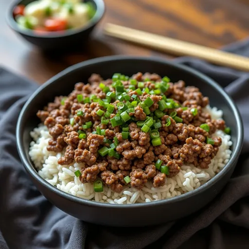 Detailed view of a Korean dish featuring ground beef, served with rice and garnished with sesame seeds and vegetables.