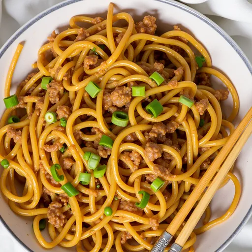 Delicious vegan garlic noodles topped with green onions, shot in natural light with a blurred background.
