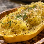 Juicy baked spaghetti squash displayed from the side, showcasing its golden-yellow flesh.