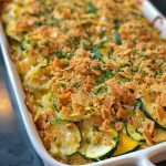 A close-up view of a buttery zucchini casserole topped with crushed Ritz crackers.
