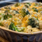 A close-up side view of cheesy broccoli cauliflower casserole with a golden crust.