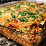 Close-up view of a vibrant Chicken Enchilada Casserole topped with melted cheese and green onions.