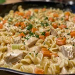 Close-up of a creamy chicken noodle skillet filled with noodles and vegetables.