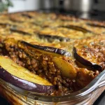 Close-up view of a slice of Vegan Moussaka showcasing layers of lentils, eggplant, and creamy sauce.