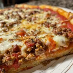 A close-up side view of a slice of Weight Watchers Deep Dish Pizza showcasing layers of cheese and toppings.
