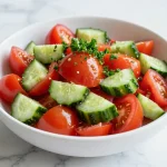 A vibrant tomato and onion salad in a bowl, garnished with fresh herbs