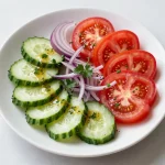 A vibrant cucumber, tomato, and onion salad drizzled with a sweet and tangy dressing