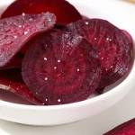 A close-up of crispy baked beet chips arranged on a wooden platter