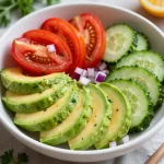 Fresh tomato, cucumber, and avocado salad in a white bowl