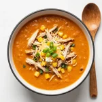A hearty bowl of slow cooker buffalo chicken chili topped with green onions and shredded cheese
