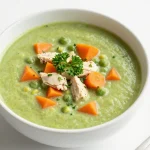 A bowl of creamy split pea soup garnished with croutons and fresh herbs