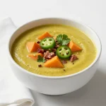 A bowl of Chili Verde with sausage and pumpkin garnished with cilantro