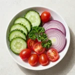 A vibrant cucumber and tomato salad served in a bowl with fresh herbs