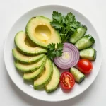 A vibrant avocado salad topped with fresh cilantro and drizzled with lime dressing